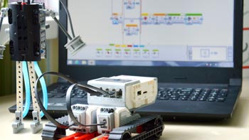Apprendre à programmer. Photo d'un robot devant un ordinateur où est ouvert le logiciel de programmation LEGO® Mindstorms